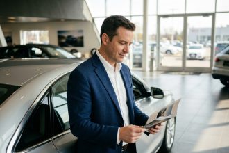 Un homme consultant une brochure dans un showroom de concession automobile moderne avec des véhicules neufs exposés