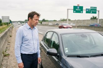 Homme d'âge moyen sur l'autoroute regardant son pare-brise fissuré